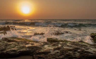 Bir yaz akşamı gün batımında kayalara çarpan dalgaların görüntüsü, İsrail, Ashkelon