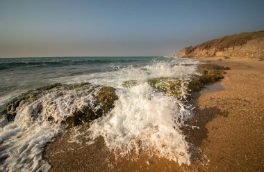 Bir yaz akşamı gün batımında kayalara çarpan dalgaların görüntüsü, İsrail, Ashkelon