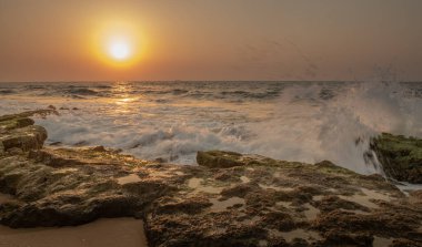 Bir yaz akşamı gün batımında kayalara çarpan dalgaların görüntüsü, İsrail, Ashkelon