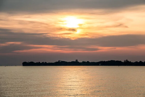 Pequeña saliva negra de tierra en el agua y una puesta de sol dorada — Foto de Stock