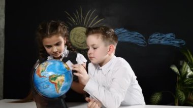 Okul kavramı. Bu bir dünya ile oynarken bir masada Schoolkids otur. Çocuklar tatilde seyahat için bir yer seçin