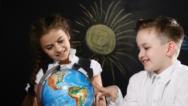 Concepto de viaje. los niños se sientan en un escritorio jugando con un globo en él. Los niños se divierten apuntando a lugares al azar eligiendo un lugar para viajar . — Vídeos de Stock