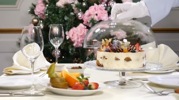 Concepto de restaurante. Festín de Año Nuevo y Feliz Navidad. Camarero en guantes se abre y luego cierra plato de vidrio con un pastel de frutas — Vídeos de Stock