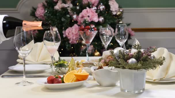 Restaurangkoncept. Nytt år och god jul fest bord. Kyparen i handskar häller champagne ur flaskan. Skivad frukt skålen och ost tallrik serveras vackert på firandet bord — Stockvideo