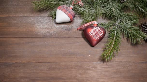Καρτ ποστάλ της Πρωτοχρονιάς και των Χριστουγέννων. Χιόνι πέφτει πάνω στο χριστουγεννιάτικο δέντρο διακόσμηση τοποθετείται σε ξύλινα φόντο. Το Top view — Αρχείο Βίντεο
