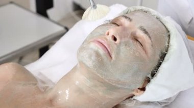 Genç kadın güzellik salonunda yordamlar almak güzel. Kanepede yatan genç güzel esmer kadın. Güzellik uzmanı yüz temizleyici köpük uygulama