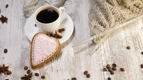 Concepto de amor. San Valentín. una taza de café recién hecho y una galleta de jengibre en forma de corazón sobre fondo de madera. La mano femenina coloca una galleta en forma de flecha cerca — Vídeos de Stock