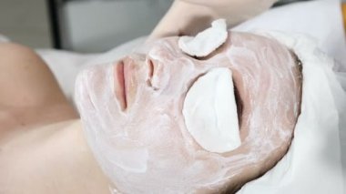 Sağlık kliniği. Genç çekici kadın profesyonel yüz bakımı alıyorum. Şevval özçelik Güzellik yüz krem maske yüz bir parmak ile yayılır. Gözler Pamuklu ped ile kapalı