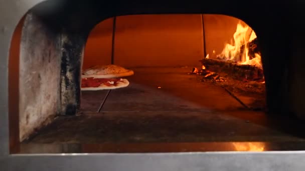 Pizza being baked in traditional wood burning pizza-bread restaurant oven. Chef pizza maker cooking pizza in restaurant open kitchen. — Stock Video