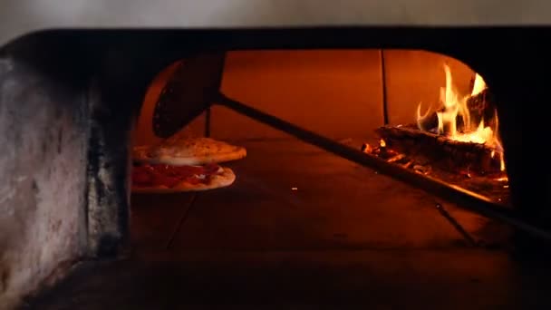 Pizza wordt gebakken in traditionele houtgestookte broodoven die pizza-restaurant. Chef-kok pizza maker koken pizza in de open keuken van het restaurant. — Stockvideo