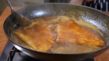 Restoran yemek kavramı. Krep karamel sos kaynar. Şefin sosu bir kaşıkla karıştırarak kapatın. Ağır çekim
