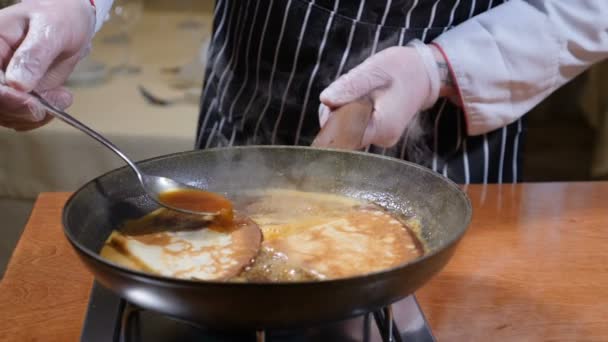 Restaurang Matlagning koncept. Pannkakor i kokande kolasås. Närbild av kocken omrörning sås med en sked. Slow motion — Stockvideo