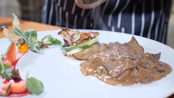 Arte de la comida. Chef añade pimienta al plato con hígado y bayas en salsa de caramelo. Movimiento lento — Vídeo de stock