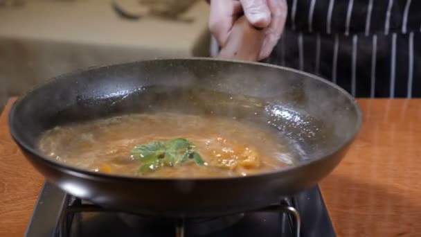 Приготовление пищи. Шеф-повар перемешивает сковороду с кипящим карамельным соусом. Медленное движение — стоковое видео