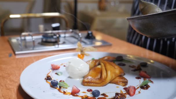 Finishing touch concept. Chef-kok giet karamel saus op een bord met dessert. Ijs, pannenkoeken en bessen worden prachtig geserveerd op een maaltijd in het restaurant. Slow motion — Stockvideo
