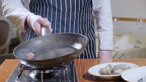 Eating out. Food preparation. Close up of chef holding a pan with boiling oil and a garlic. slow motion. oil splashes — Stock Video
