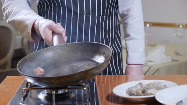 Manger dehors. Préparation des aliments. Gros plan du chef tenant une casserole avec de l'huile bouillante et un ail. au ralenti. éclaboussures d'huile — Video