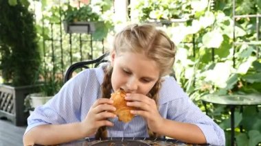 Yemek. Kruvasan yemek ve onay jesti gösterilen sevimli sevimli kız. Başparmak doldu. Mutlu çocukluk.