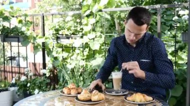 Öğle Yemeği. Tahriş olmuş şekilde telefon yakışıklı esmer genç adam görüşmeler. Masada homebaked ürünlerin çeşitli. Adam içki kahve