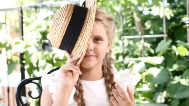 Kleine hübsche Mädchen haben Spaß mit ihrem Strohhut, der mit einem Auge zwinkert. Lebensstil. Mädchen genießen Sommertag und gute Laune — Stockvideo