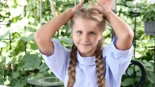 Menina bonito em um terraço aberto se divertindo mostrando orelhas com as mãos. Feliz infância. A rir. desfrutando de dia ensolarado 4k — Vídeo de Stock