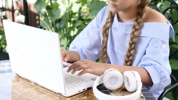 Retrato de una chica atractiva usando un portátil blanco escribiendo una carta. auriculares en la mesa. 4k — Vídeos de Stock