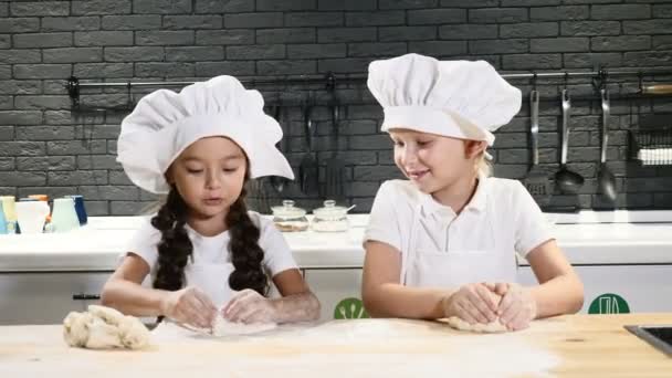 Cozinhar faz troça. Duas crianças pequenas cozinham juntas, rolando doudh com as mãos, fazendo pizza. 4k — Vídeo de Stock