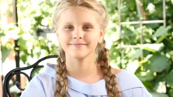 Videoporträt eines entzückenden Mädchens im Stadtpark, das die sonnige Tagessonne genießt. hübsche Schulmädchen lächelt in die Kamera. 4k — Stockvideo