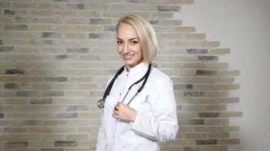 Bir phonendoscope boyun kamera gülümseyen seyir ile genç güzel kadın doktor portresi. Sağlık Bakım Metodolojisi. 4k