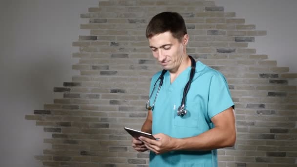 Retrato de jovem médico masculino em uniforme médico verde se divertindo. Jovem especialista vestindo fonendoscópio no pescoço. 4k — Vídeo de Stock