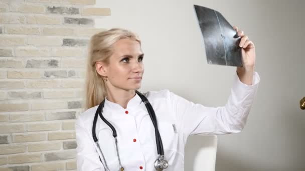 Health Examination. Young female doctor in her office. Friendly ENT Pediatrician. Doctor with a phonendoscope on neck examining x ray image 4k — Stock Video