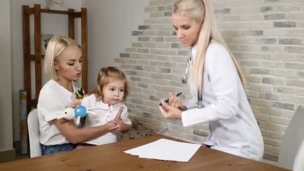 Vriendelijke kinderarts krijgen kennis met jonge moeder en haar mooie dochter. Familie kliniek concept. 4k — Stockvideo
