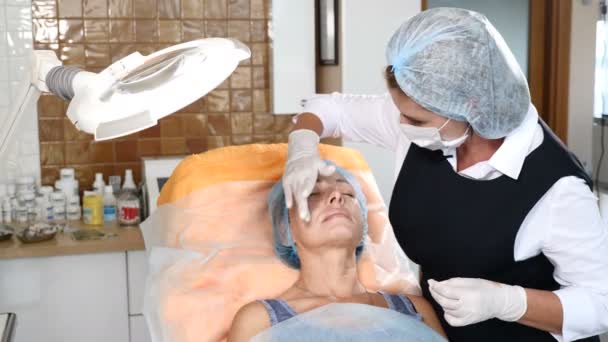 Beautician Applying Anesthesia to a senior female client. woman getting ready for beauty treatment. 4k — Stock Video