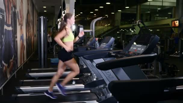 Edzéstervek. Yong professzionális női trainer cardio gyakorlatokat az edzőteremben csinál. 4k — Stock videók
