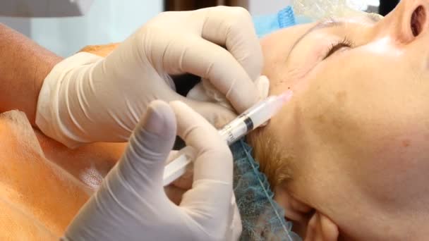 Injections de mésothérapie. Une vieille femme se fait opérer le visage. Esthéticienne professionnelle avec une seringue dans les mains faisant des injections de beauté . — Video