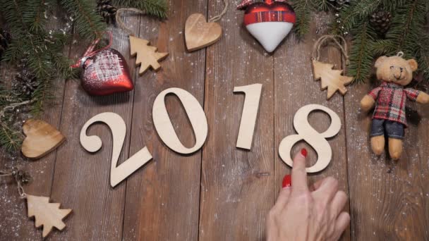 З Різдвом і новим роком 2019 концепції. 2018 дерев'яні символи розміщено на фону з соснових гілок дерев та новорічних іграшок. Жіночий рука зміни рисунок 8 на 9 у 2019 числових символів. HD — стокове відео