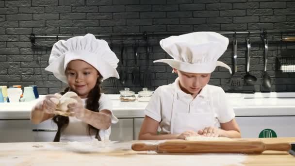 Kinderen spelen volwassen beroepen. kleuters in schorten en chef-kok caps koken in de keuken thuis. Koken thuis concept. 4k — Stockvideo