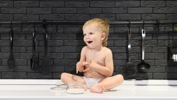 Счастливого детства. Милый мальчик, сидящий на столе и дегустирующий сахар и сладости пальцем. 4k — стоковое видео
