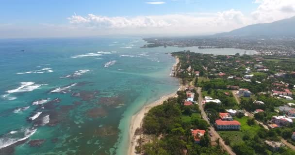 Volando sobre hermosas olas del océano a la costa exótica con casas y palmeras. 4k. Vista superior — Vídeos de Stock