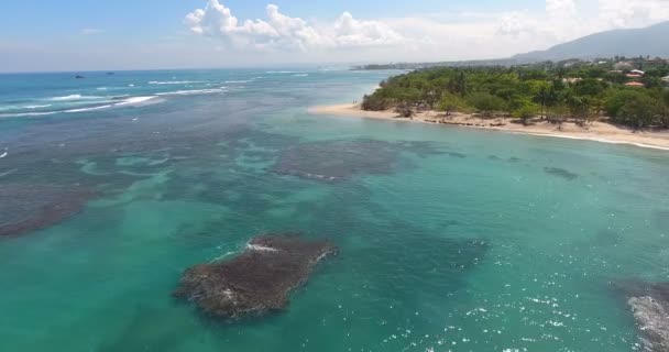 Volando sobre hermosas olas del océano a la costa exótica con casas y palmeras. 4k. Vista superior — Vídeos de Stock