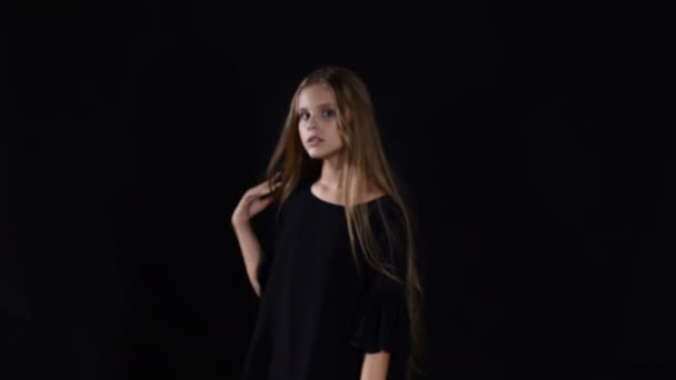 Portrét teenagera promyšlené modelka pózuje při pohledu na fotoaparát. Dívka na černém dotýká vlasů předstírala dospělého. 4k — Stock video