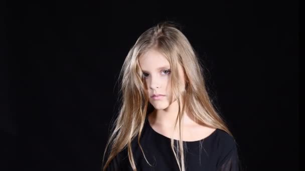 Menina modelo posando no fundo preto. Adolescente loira de cabelos compridos olhando para a câmera mostrando emoção facial. 4k — Vídeo de Stock