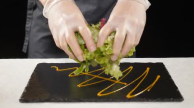 Ağır çekimde yemek yeşil salata. Sağlıklı marul ile yeşil salata ve domates hazırlanıyor. Şef taze koyarak eldiven marul ağır çekimde plaka üzerinde karışımı. HD