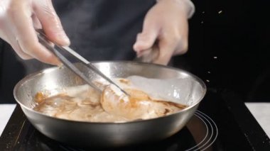 Şef yemek. Ocak eldiven içinde deniz ürünleri hazırlar. Fistolar krema soslu tavada kaynar. HD