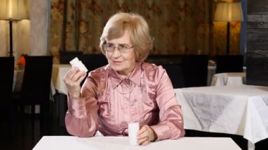 Eller tıpta bakarak bir yaşlı kadın. Yetişkin hayat kavramı. Etiket okuma hoş görünümlü kadın kıdemli. 4k