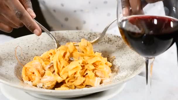 Concepto de comida. Primer plano de macho afroamericano comiendo pasta con una cuchara y un tenedor. una copa de vino está en la mesa. Concepto de vacaciones y restaurante. 4k — Vídeos de Stock