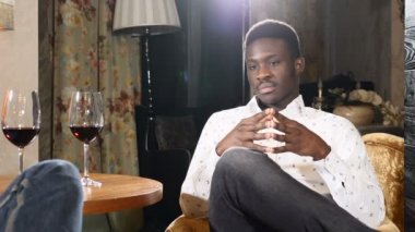 Arkadaşı ile konuşurken restoranda oturan Afrikalı-Amerikalı genç adam video portre. Gözlük masada kırmızı şarap ile. Toplantı arkadaşlar kavramı. 4k
