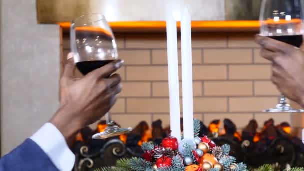 Vacances, nouvelle année et concept de célébration. Mains masculines cliquetis verres de vin rouge à Noël. Cheminée confortable à l'arrière-plan. 4k — Video