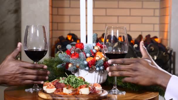 Férias, ano novo e conceito de celebração. Mãos masculinas segurando copos de vinho tinto no Natal. Lareira acolhedora ao fundo. 4k — Vídeo de Stock