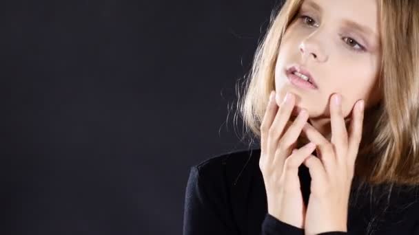 Portrait of cute female teenager posing on black background with her hands touching face. Sensetive shot. 4k — Stock Video